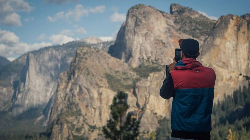 hiker taking photo of mountain with iphone