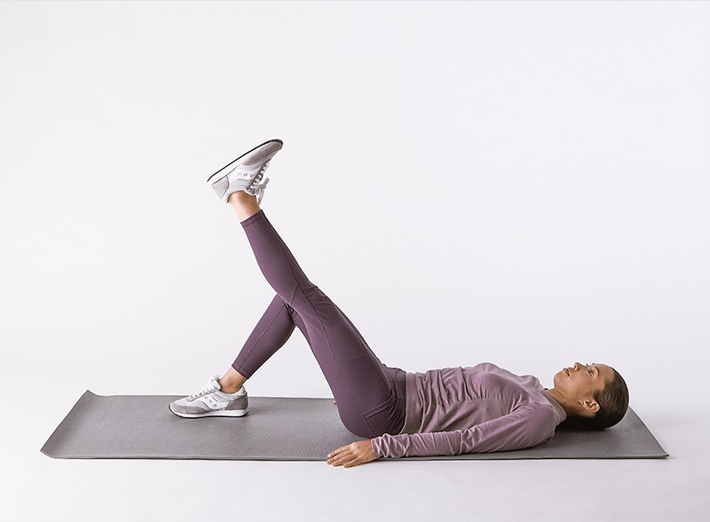 woman doing straight leg raise on yoga mat