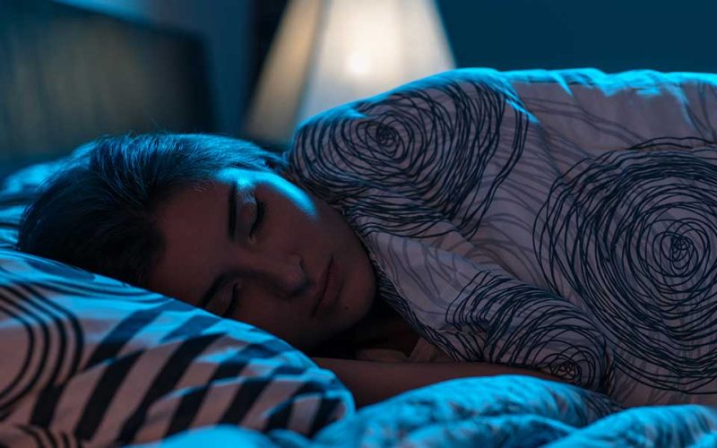 young-woman-sleeping-bed-dark-bedroom
